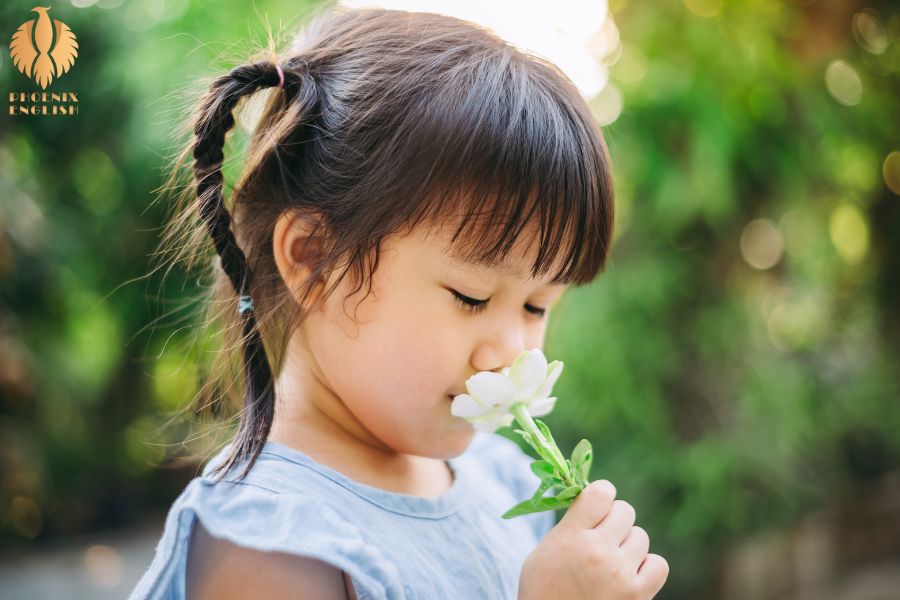 an pic about A little girl who is smelling a flower